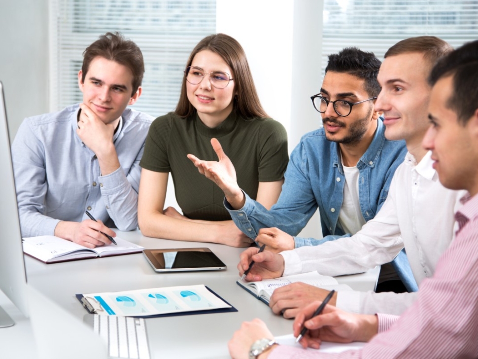 la imagen muestra a 5 personas mirando una pantalla de computadora.