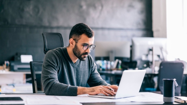 imagem mostra um homem fazendo contas em um notebook.