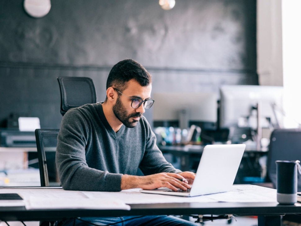 imagem mostra um homem fazendo contas em um notebook.