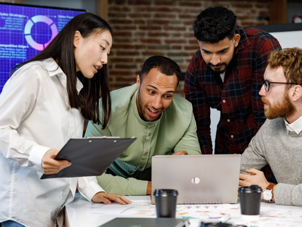 la imagen muestra a cuatro personas alrededor de un cuaderno hablando sobre finanzas.