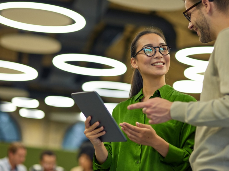 la imagen muestra a una mujer sonriendo junto a un hombre con una tableta en la mano.