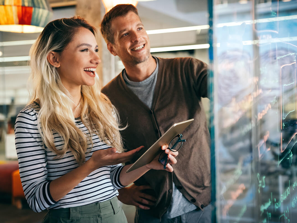 la imagen muestra a una mujer y un hombre sonrientes en una oficina.