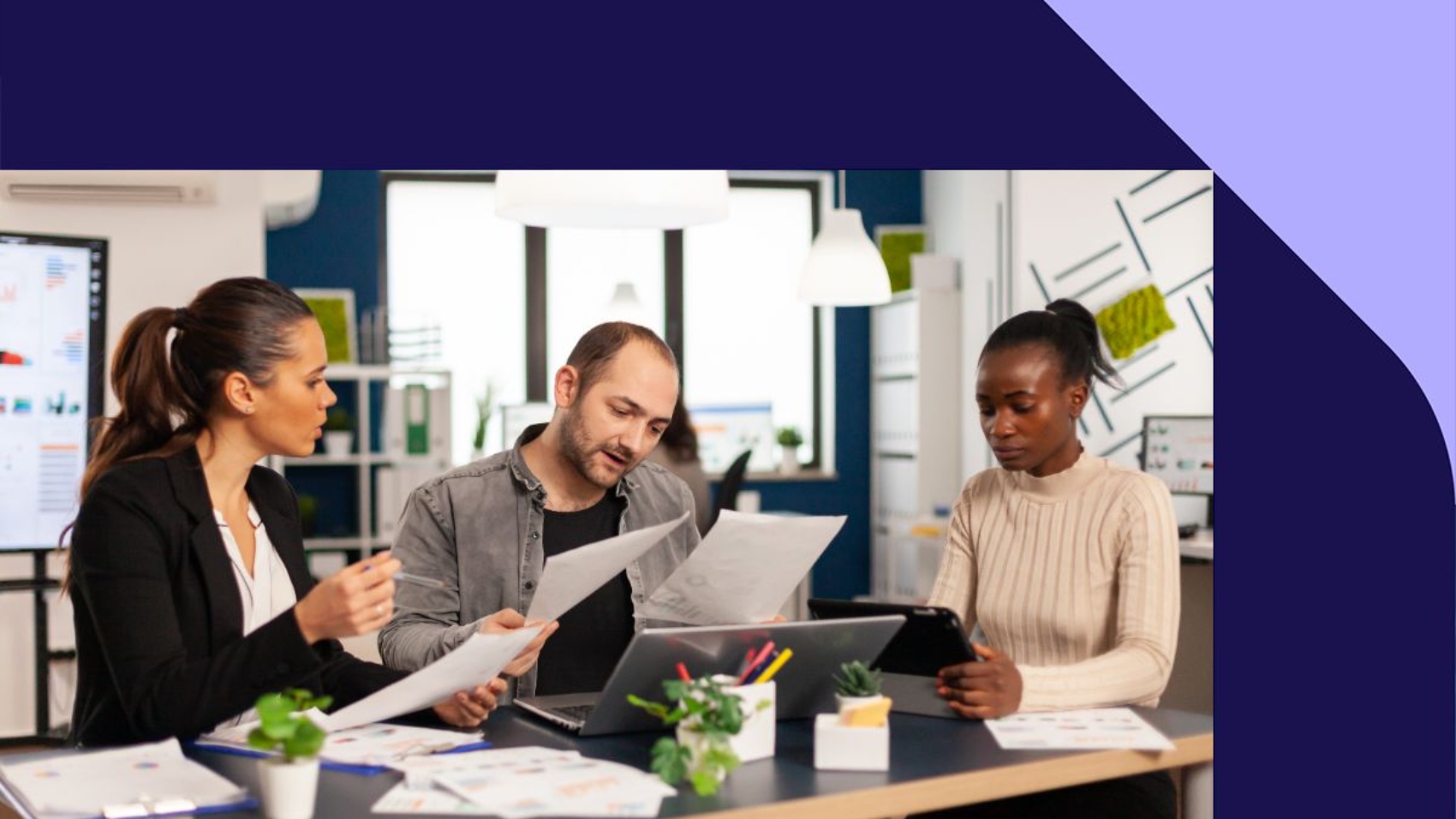 imagem mostra duas mulheres e um homem no escritório analisando documentos financeiros.